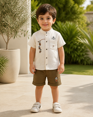 Toddler boy wearing a cream embroidered mandarin-collar shirt and brown shorts set