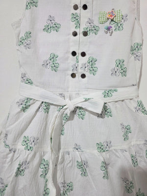 Close-up of Inaabia white floral girls dress showing dark buttons, waist tie bow and decorative floral applique