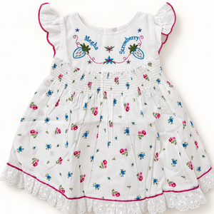 White floral baby dress showing embroidered bodice, shirred waist and lace trim