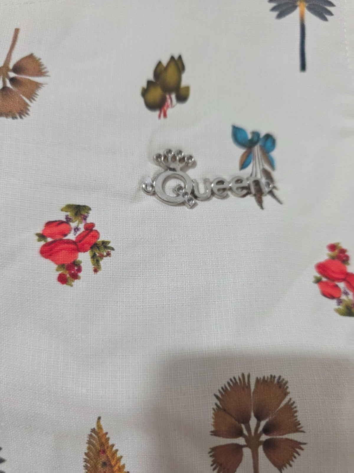 Close-up of ivory botanical girls dress showing Queen chest embellishment
