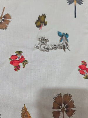 Close-up of ivory botanical girls dress showing Queen chest embellishment