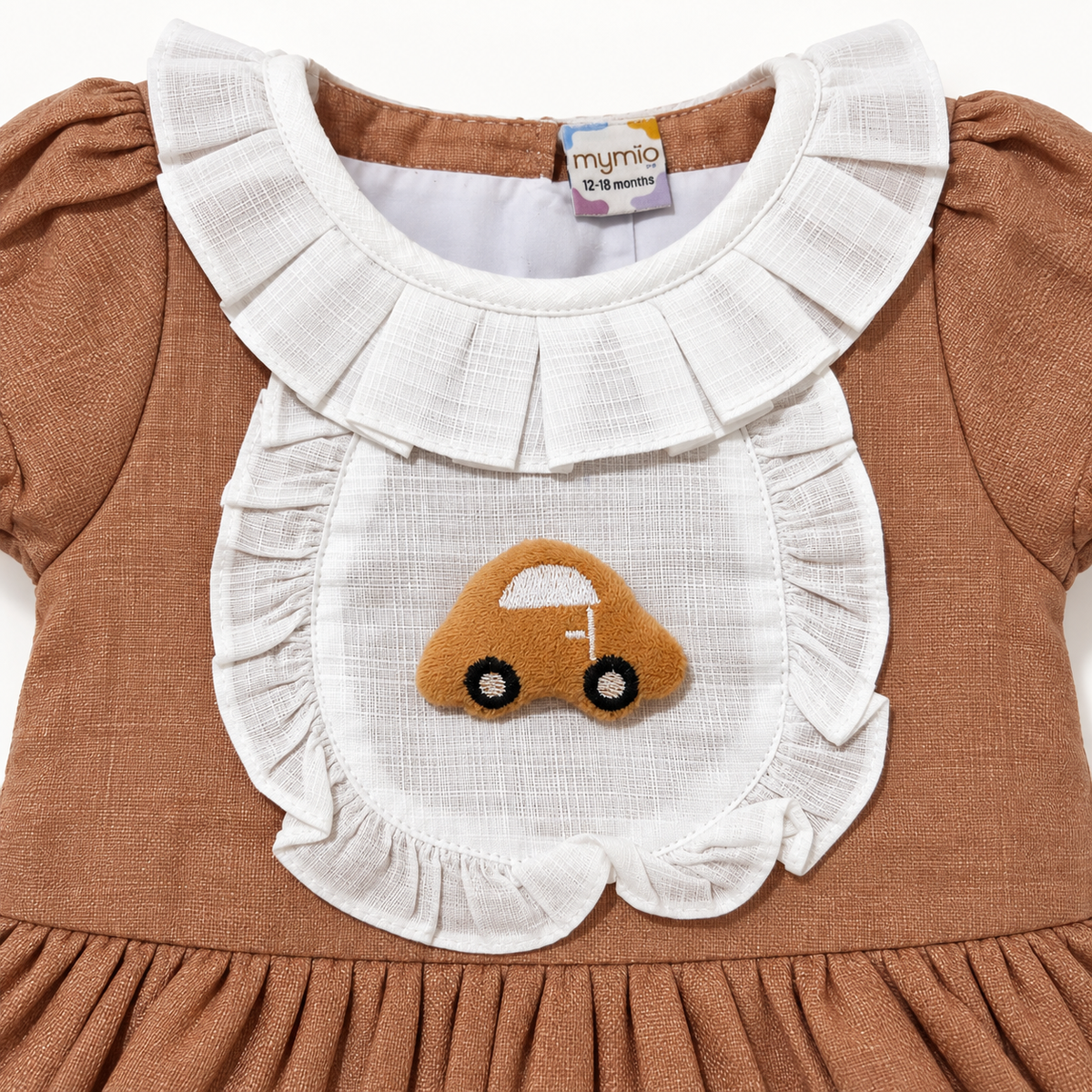 Close-up of brown dress white ruffled bib and textured car applique