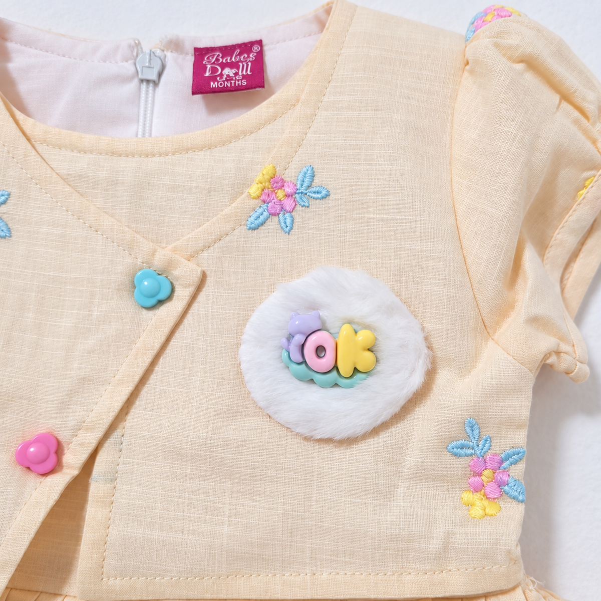 Peach dress floral embroidery, flower buttons and fluffy badge detail