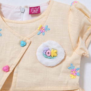 Peach dress floral embroidery, flower buttons and fluffy badge detail